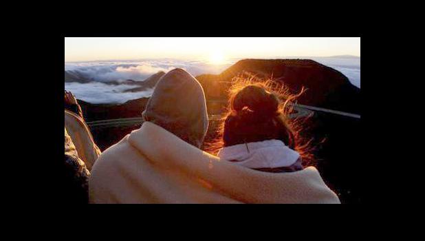 A couple watches as the sun rises in front of the summit of Haleakala volcano in Haleakala National Park on Hawaii's island of Maui, Sunday, Jan. 22, 2017. Sunrise viewing has long been popular at Haleakala, one of the main attractions at Haleakala National Park despite morning temperatures that often dip into the 30s. (AP Photo/Caleb Jones)