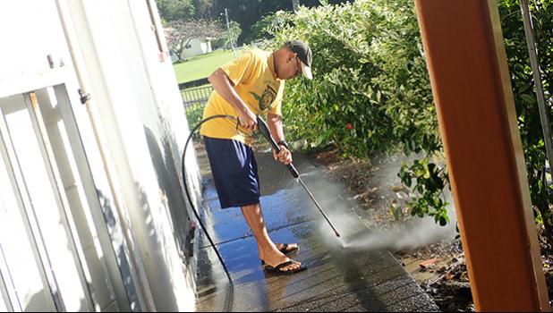 Niulaititi Hopkinson power washing the area outside of the Fatuoaiga Montessori School