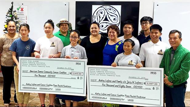 Students of Onnuri Piano Academy — together with members of American Samoa's Korean and Chinese Associations, and the Korean and Chinese Community Youth Groups — pictured with two checks