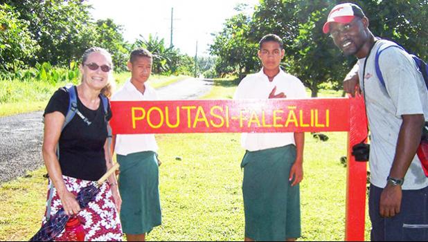 Peace Corps volunteers infron of Poutasi Village sign 