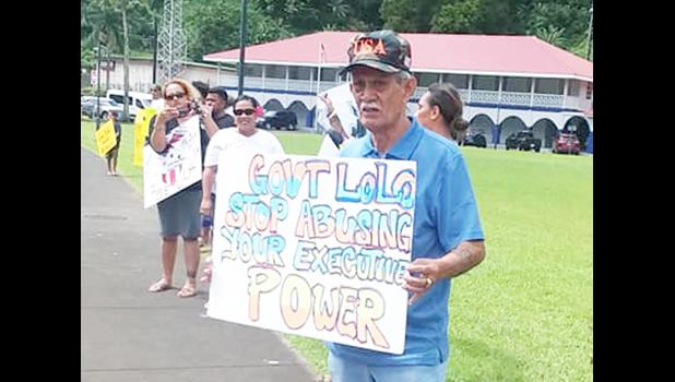 Pago Pago High Chief Pulu Ae Ae Jr. holds up a sign that reads: “Gov. Lolo: Stop abusing your executive power"