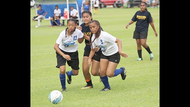 Two Samoana players defend against a Fa’asao-Marist opponent 