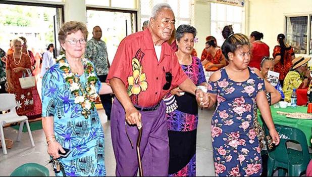 Evelyn Lili’o Satele (left) helps escort an elderly member of the community