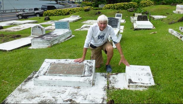 Tom Blake touches the two gravestones in Pago Pago, of his friend Mark Flannery’s parents