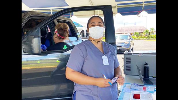 Healthcare worker with mask standing beside a car