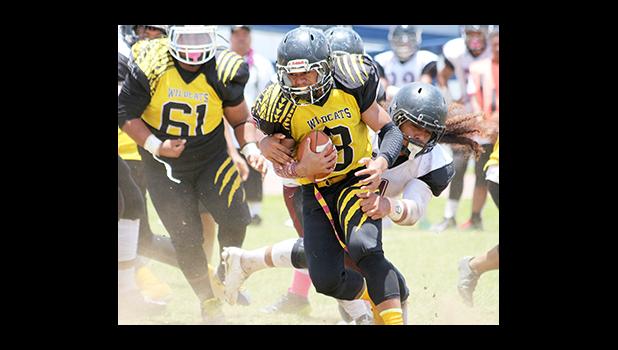 Wildcats Fa’asau Mareko, immediately wrapped up in the backfield, by Tafuna’s Penei Stowers-Pavihi, in the opening half of their Varsity game last Saturday. Tafuna’s Senior Game ended tragically after Mareko led the Wildcats to victory in their 28 - 20 win, the biggest upset of the season.  [photo: TG]