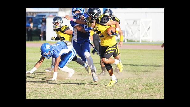 Nu’uuli Wildcats Hans Misa gets apprehended by Fa’au Seumanutafa of the Sharks at the line of scrimmage on a draw play – a tackle that prevented a first down opportunity for the Wildcats in the opening half of their Varsity game last Friday evening.  [photo: TG]