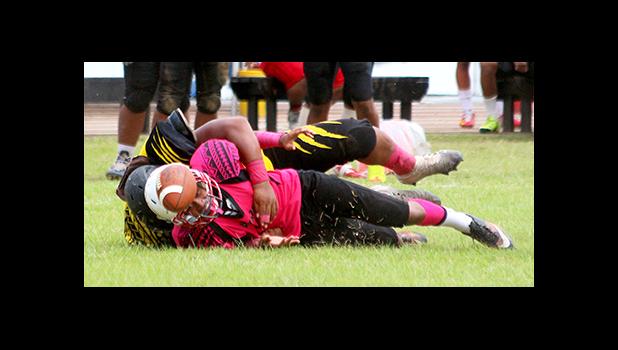 John Muliaga of Faga’itua watches the live ball helplessly after being rocked hard by Branson Pualau in the second quarter of the match – causing a fumble that carried Nu’uuli into Vikings territory for another threatening offensive drive.  [photo: TG]