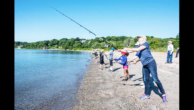 Janet Coit casts her line into the water with others in background
