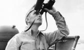 This October 1942 file photo shows Eugene Burns, Associated Press war correspondent with the Pacific Fleet, on the deck of a Navy vessel with binoculars raised as he covered operations of a task force in the South Pacific. On Dec. 7, 1941, as Japanese bombs rained down on Pearl Harbor, Burns, Associated Press chief of bureau in Honolulu, was unable to get out the urgent news of the historic attack that would draw the U.S. into World War II. The military had already taken control of all communication lines, so Burns was left without a line to the outside world. (AP Photo) This October 1942 file photo shows Eugene Burns, Associated Press war correspondent with the Pacific Fleet, on the deck of a Navy vessel with binoculars raised as he covered operations of a task force in the South Pacific. On Dec. 7, 1941, as Japanese bombs rained down on Pearl Harbor, Burns, Associated Press chief of bureau in Honolulu, was unable to get out the urgent news of the historic attack that would draw the U.S. into World War II. The military had already taken control of all communication lines,