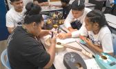 Irene assists BGCAS Music Club members learn how to string their ukuleles.