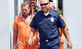 Dean J. Fletcher (left) is escorted by a police officer after his initial appearance in District Court yesterday. According to media reports, Fletcher is wanted by Tongan authorities for murder in the island Kingdom.  [photo: AF]