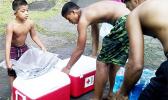 Members of a family in Fagasa, who lost their home to a fire on Aug. 30th, taking coolers packed with emergency supplies and cases of bottled water and other necessities from the local American Red Cross office.  [photo: local Red Cross]