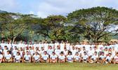Samoana High School – "Home of the Sharks" Football Program, both the Varsity and Junior Varsity put together, alongside Head Coach Pati Pati (far right) and his coaching staff, at the conclusion of practice yesterday evening at their school field. The Sharks will be making their initial appearance for the season in their match up against the Warriors tomorrow afternoon. “Shark Up Go Blue” says Pati to supporters. [photo: TG].