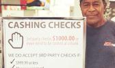 ACE employee beside their check chasing policy sign