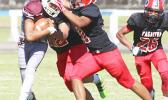 Warriors quarterback Francisco Mauigoa being devoured by two of Faga’itua’s most vicious defensive fronts, during the opening half of the JV game last Saturday.  [photo: TG]