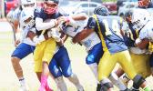 The playmaker for the Wildcats, Iosefa Mauga is stopped immediately by a host of Samoana Sharks behind the line of scrimmage for a loss during the third quarter of their varsity match up last Saturday morning. Samoana’s defensive unit shut out the Wildcats completely in a 49-0 victory, the first team to ever shut out Nu’uuli this regular season.  [photo: TG]