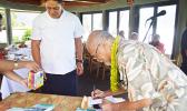 Fuimaono Fini Aitaoto signing the cover of his book