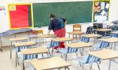 A DOE employee cleaning a classroom