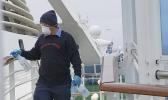 In this photo provided by Michele Smith, a A Thursday, March 5, 2020, off the California coast. Scrambling to keep the coronavirus at bay, officials ordered a cruise ship with about 3,500 people aboard to stay back from the California coast Thursday until passengers and crew can be tested, after a traveler from its previous voyage died of the disease and at least two others became infected. (Michele Smith via AP) A cruise ship worker cleans a railing on the Grand Princess