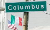 Street sign that says Columbus with flags in background