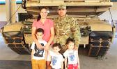 DeAngelo Herrera and family posing in front of a tank