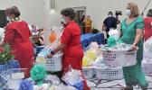 Three female staff members carrying gift baskets into Hope House