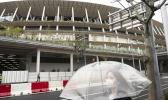 A woman walks past the New National Stadium, a venue for the opening and closing ceremonies at the Tokyo 2020 Olympics, in Tokyo, Monday, March 23, 2020. The IOC will take up to four weeks to consider postponing the Tokyo Olympics amid mounting criticism of its handling of the coronavirus crisis that now includes a call for delay from the leader of track and field, the biggest sport at the games. (AP Photo/Jae C. Hong) A woman walks past the New National Stadium, a venue for the opening and closing ceremonies at the Tokyo 2020 Olympics