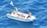 Two men in small boat waving overhead at airplane unseen in photo