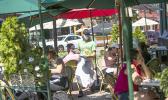 A waiter in a face mask delivers food to the tables outside of a restauran