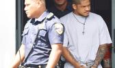 Manu Lefatia in handcuffs escorted by two police officers