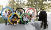 A group of students from Uruguay pose for a souvenir picture on the Olympic Rings set outside the Olympic Stadium in Tokyo, Saturday, March 21, 2020. The Olympic flame from Greece arrived in Japan Friday, even as the opening of the the Tokyo Games in four months is in doubt with more voices suggesting the games should to be postponed or canceled because of the worldwide virus pandemic. (AP Photo/Gregorio Borgia) A group of students from Uruguay pose for a souvenir picture on the Olympic Rings set outside the Olympic Stadium in Tokyo