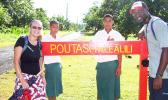 Peace Corps volunteers infron of Poutasi Village sign 