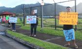 Three protesters with signs protesting governer's checks to fono