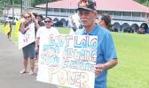 Pago Pago High Chief Pulu Ae Ae Jr. holds up a sign that reads: “Gov. Lolo: Stop abusing your executive power"