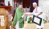 shows Tualauta Faipule Larry S. Sanitoa (right) shaking hands with Bishop Kolio Etuale Tumanuvao,