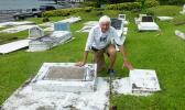 Tom Blake touches the two gravestones in Pago Pago, of his friend Mark Flannery’s parents